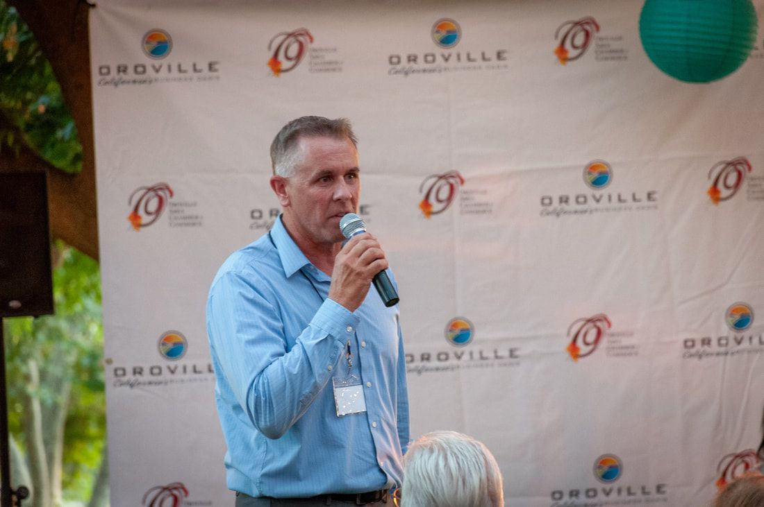 A man is holding a microphone in front of a wall with logos on it.