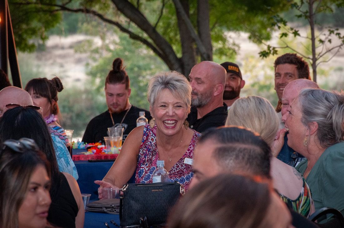 A group of people are sitting at tables laughing and smiling.