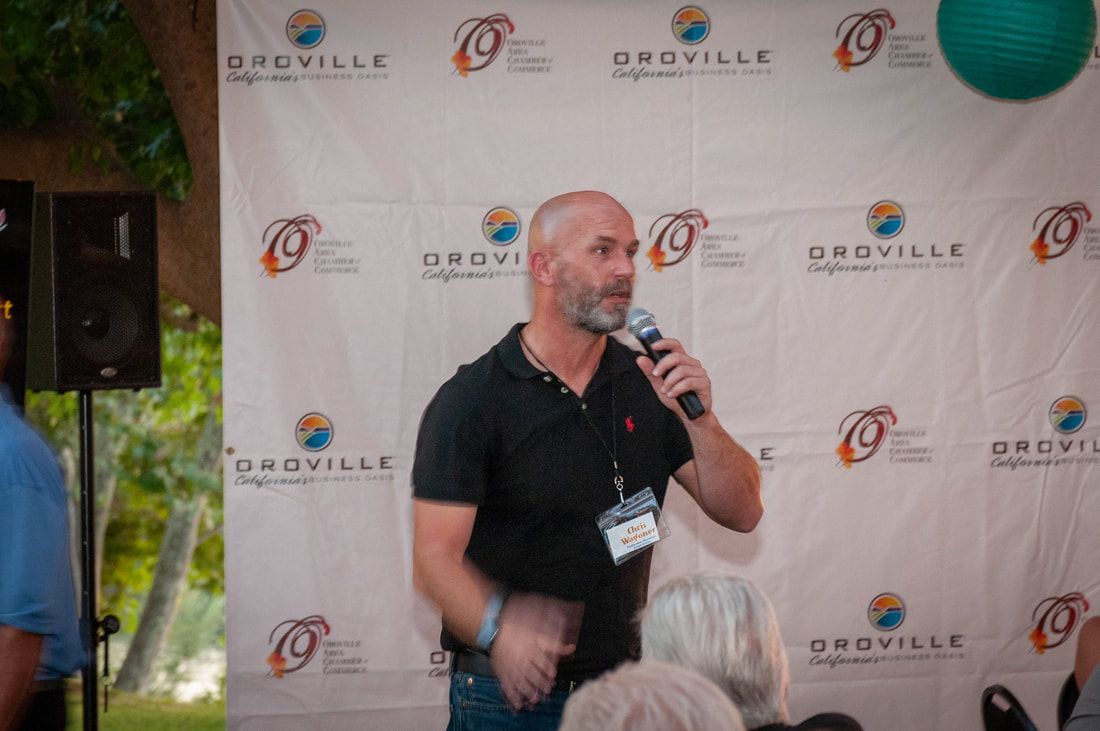 A man is standing in front of a wall holding a microphone.