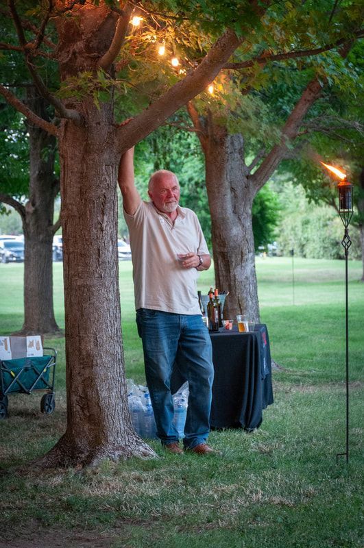 A man is leaning against a tree in a park.