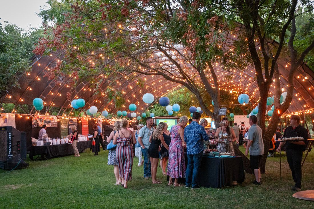 A group of people are standing under a tent in a park.