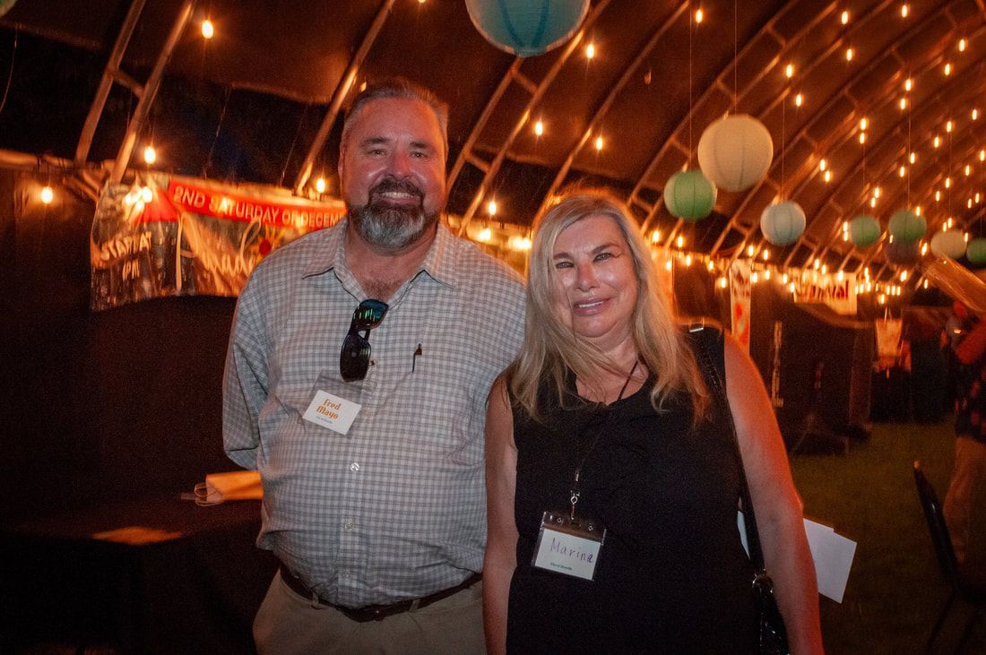 A man and a woman are posing for a picture in a tent.