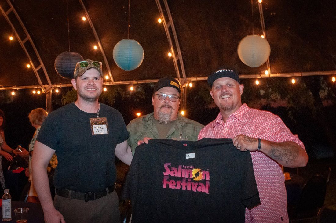 Three men are holding a salmon festival t-shirt