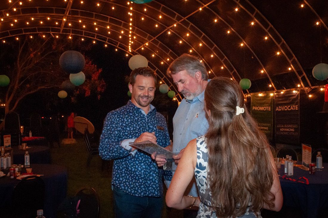 A group of people are standing under a canopy with lights.