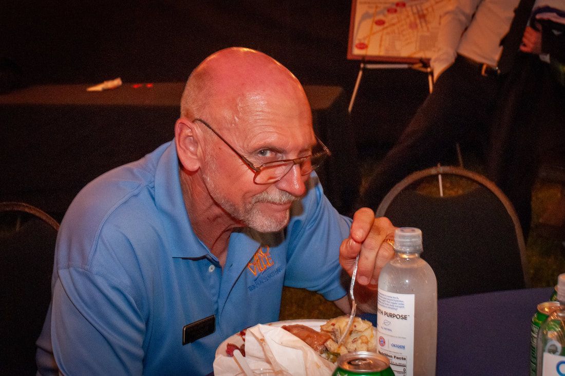 A man is sitting at a table with a plate of food and a bottle of water.