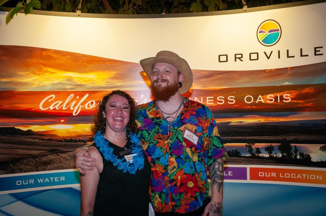 A man and a woman are posing for a picture in front of a wall.