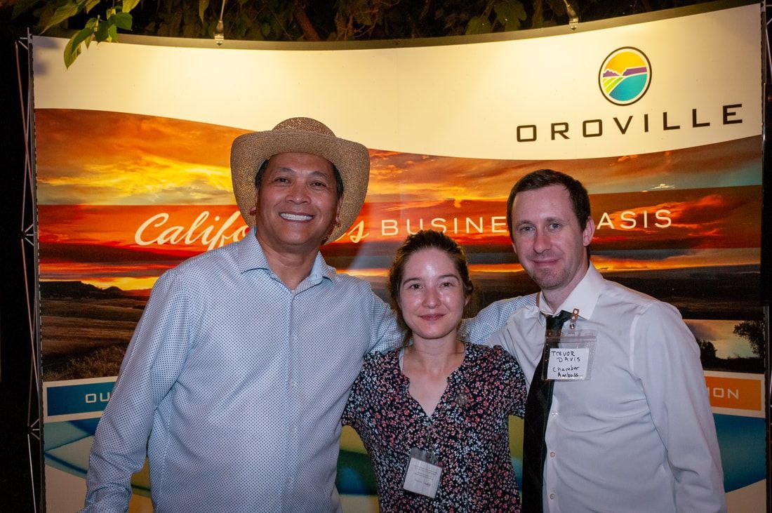 Three people posing for a picture in front of a sign that says oroville