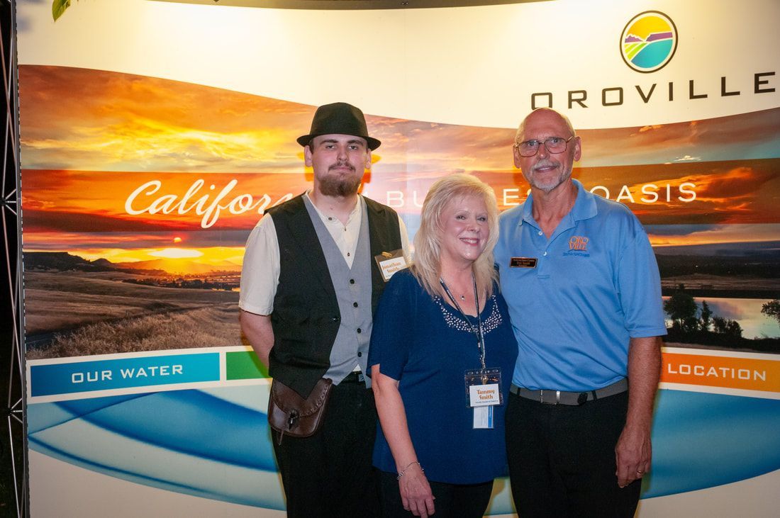 Three people are posing for a picture in front of a california sign