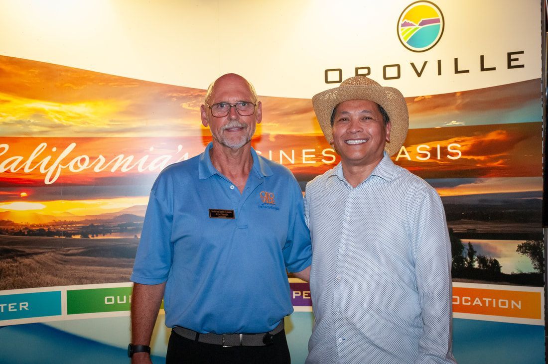 Two men are posing for a picture in front of a sign that says oroville