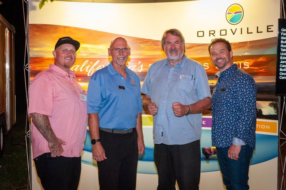 Four men are posing for a picture in front of a sign that says droville