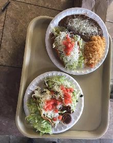 Two plates of mexican food are on a tray.