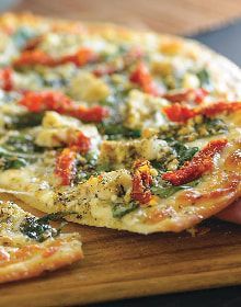 A person is taking a slice of pizza from a pizza on a cutting board.
