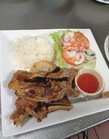 A plate of food with meat , rice and vegetables on a table.