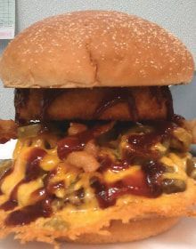 A close up of a hamburger with cheese and sauce on a bun