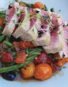 A close up of a plate of food with meat and vegetables on a table.