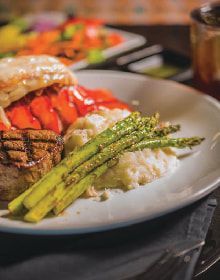 A close up of a plate of food with asparagus and mashed potatoes on a table.