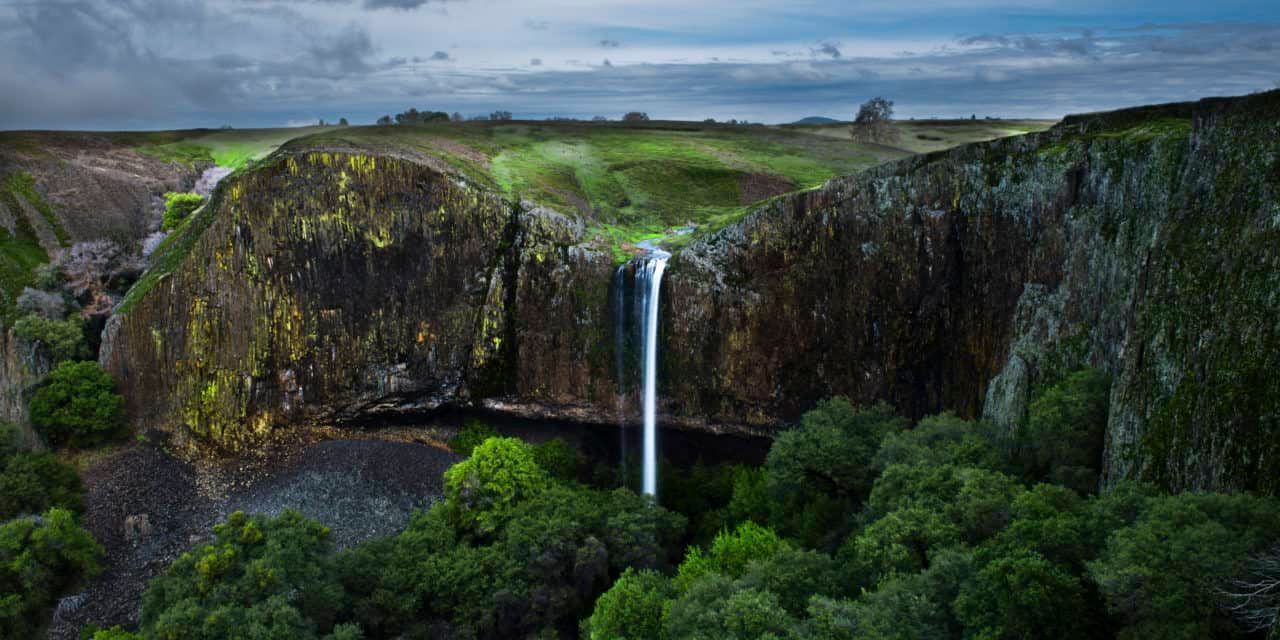 An aerial view of a waterfall in the middle of a forest.