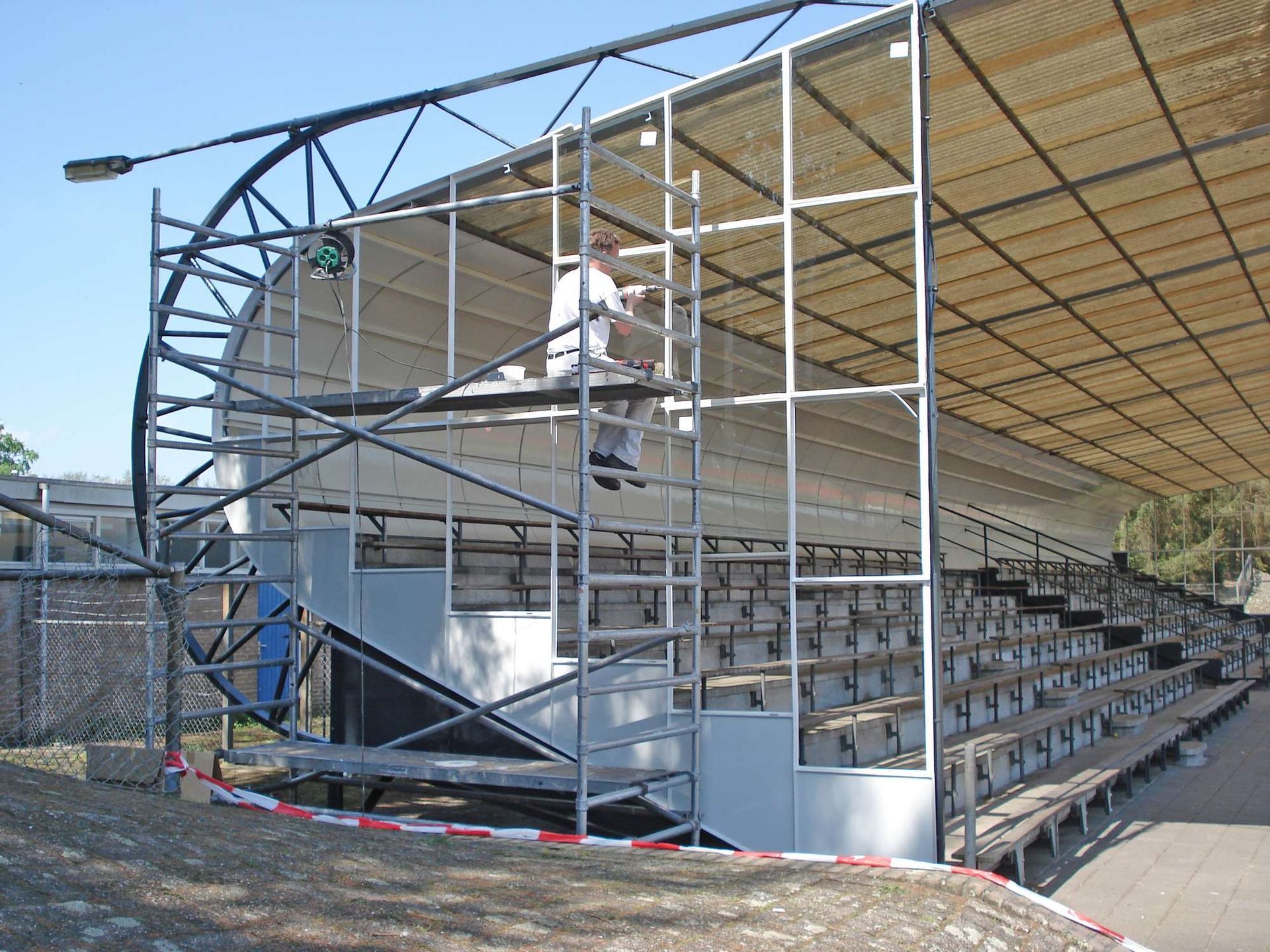 Iemand werkt op een trapsgewijze, openluchtconstructie met een gebogen steun. 