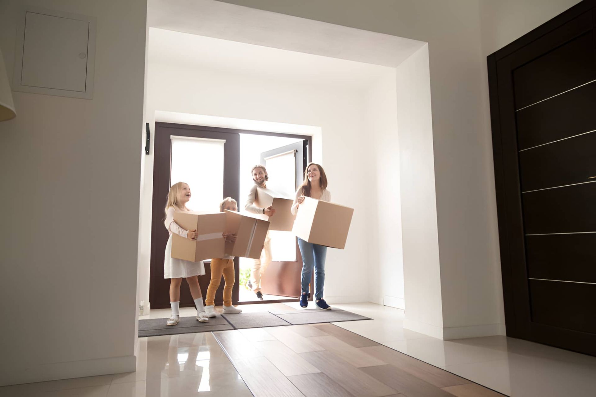 A Family is Carrying Cardboard Boxes Into a New Home — MoneySmith Group In Pottsville, NSW