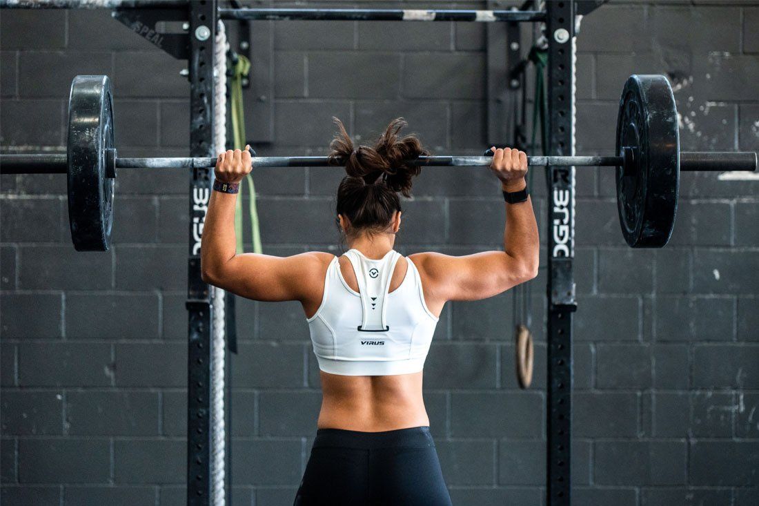 A Woman is Lifting a Barbell Over Her Head in a Gym — MoneySmith Group In Kingscliff, NSW