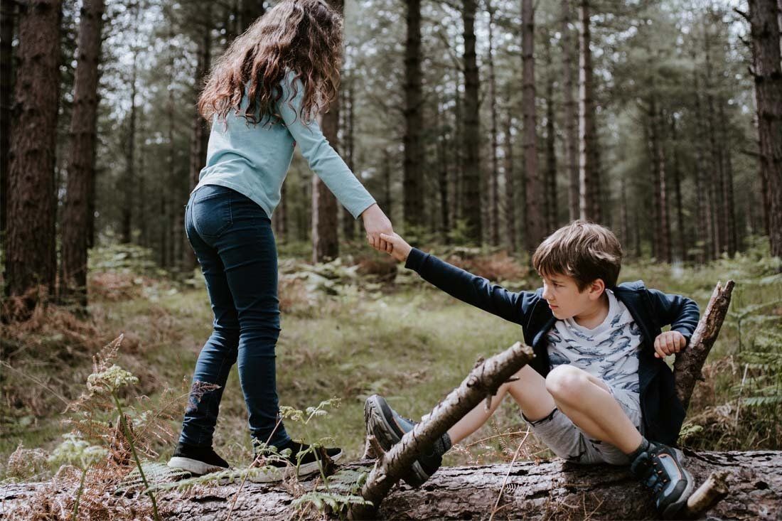 Girl is Helping a Boy Climb a Log in the Woods — MoneySmith Group In Kingscliff, NSW
