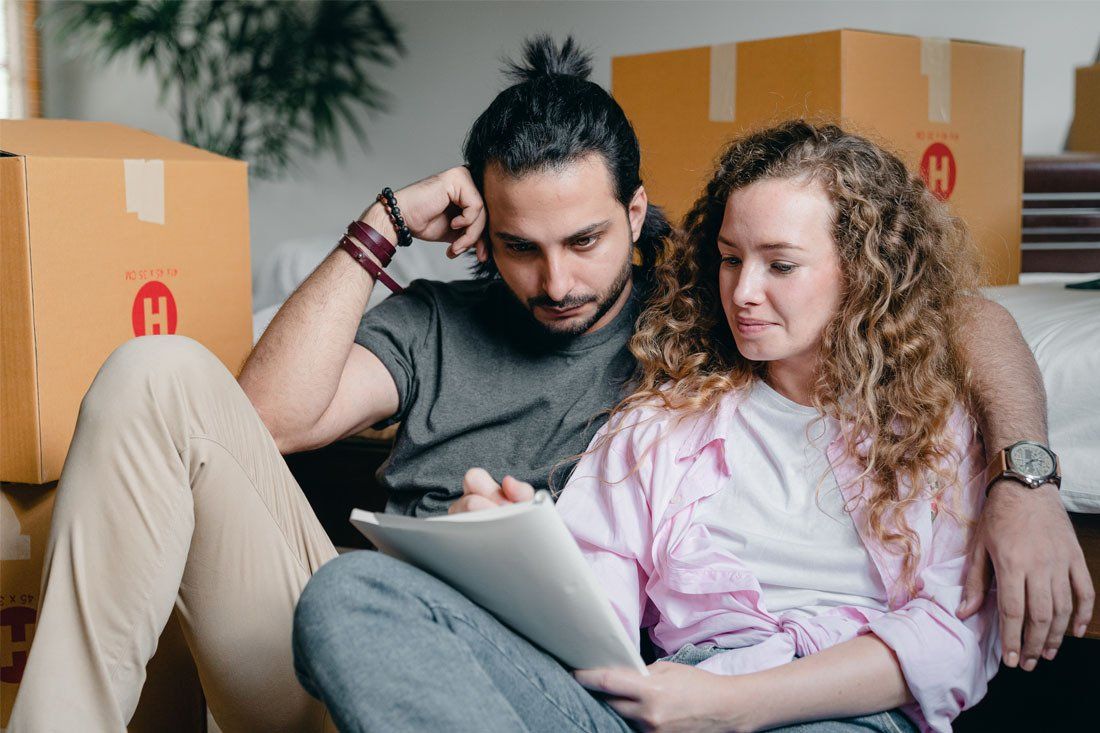 Man and a Woman Are Sitting on the Floor Looking at a Table — MoneySmith Group In Kingscliff, NSW