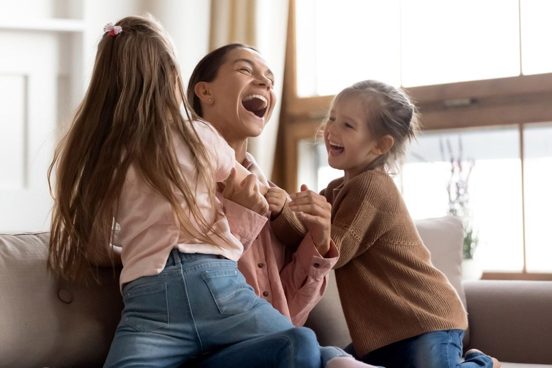 A Woman and Two Little Girls Are Playing on a Couch — MoneySmith Group In Kingscliff, NSW