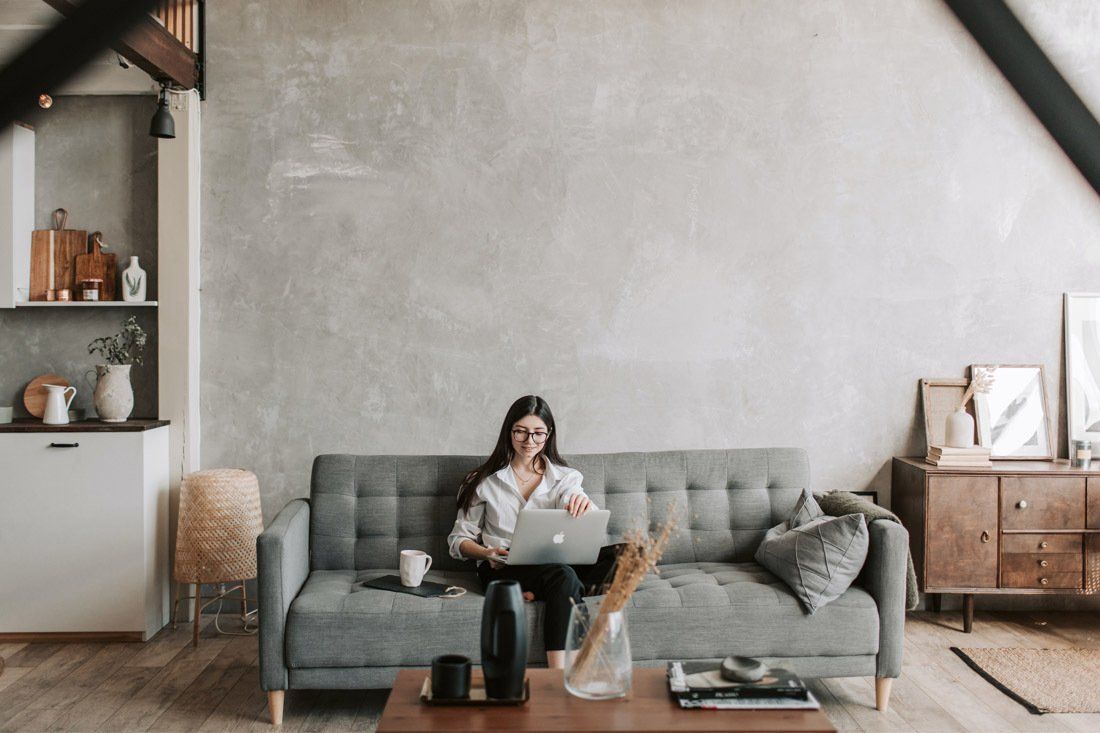 Woman is Sitting on a Couch Using a Laptop Computer — MoneySmith Group In Kingscliff, NSW