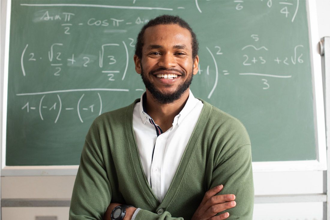 A Man is Standing in Front of a Blackboard in a Classroom — MoneySmith Group In Kingscliff, NSW