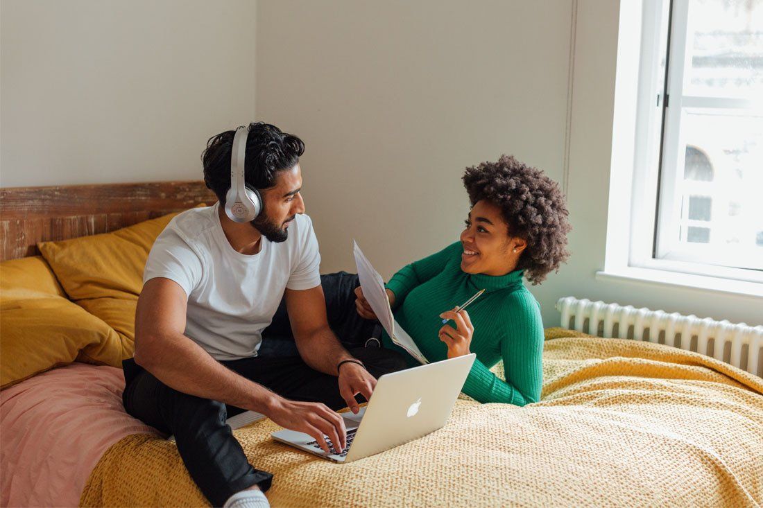 Man and a Woman Are Sitting on a Bed With a Laptop — MoneySmith Group In Kingscliff, NSW