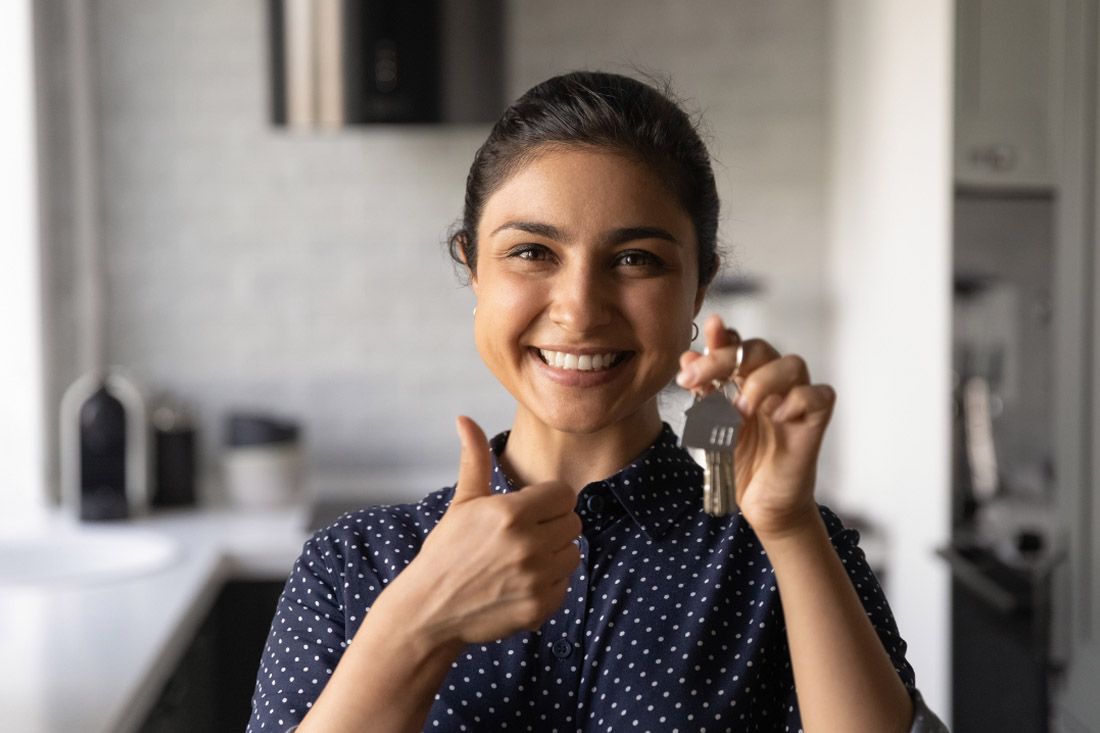 A Woman is Holding a Key and Giving a Thumbs Up — MoneySmith Group In Kingscliff, NSW