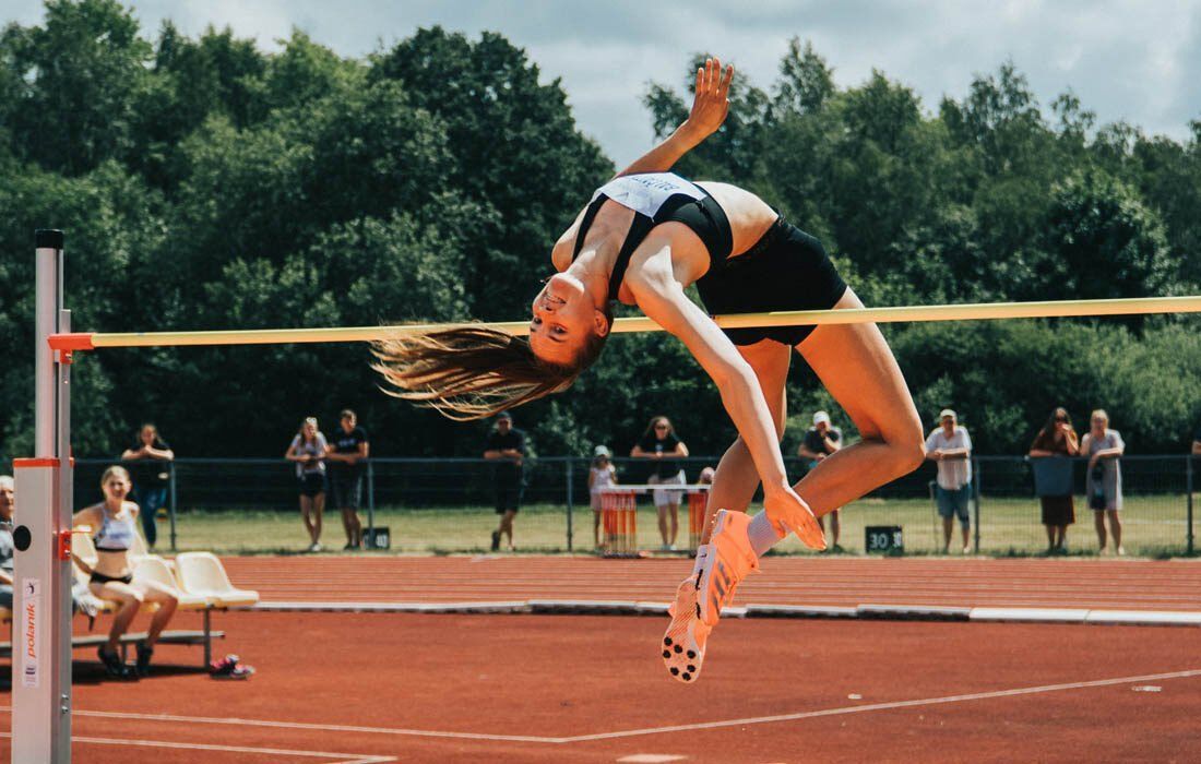 Woman is Jumping Over a Pole on a Track — MoneySmith Group In Kingscliff, NSW