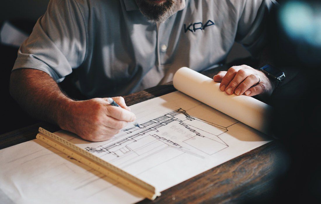 A Man is Sitting at a Table Drawing on a Piece of Paper — MoneySmith Group In Kingscliff, NSW