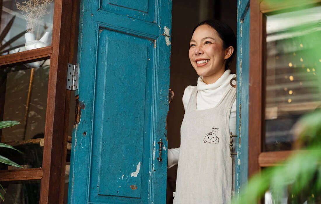A Woman is Smiling While Standing in a Blue Door — MoneySmith Group In Kingscliff, NSW