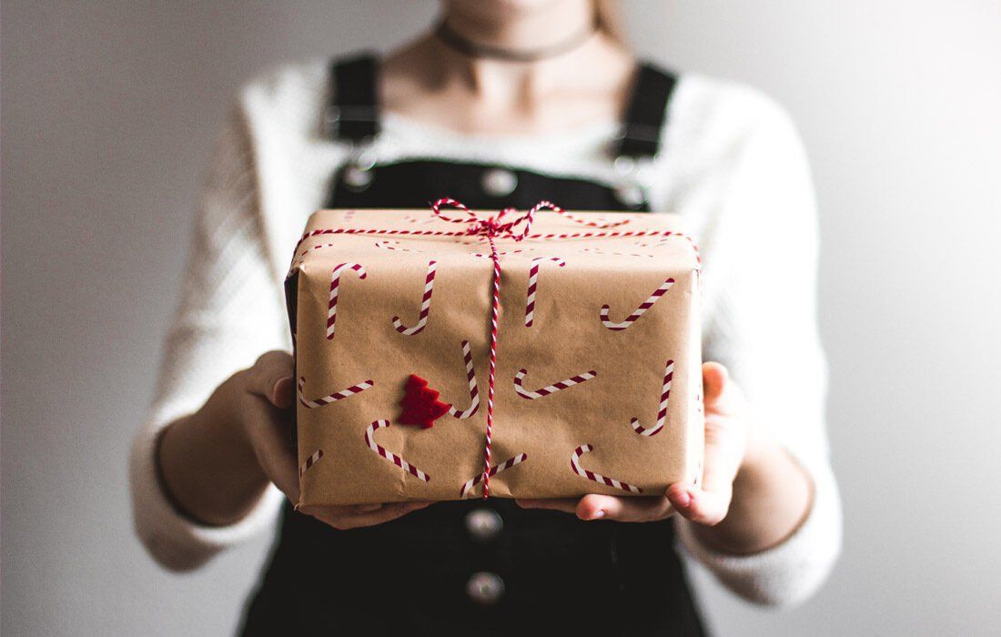 A Woman is Holding a Wrapped Gift — MoneySmith Group In Kingscliff, NSW