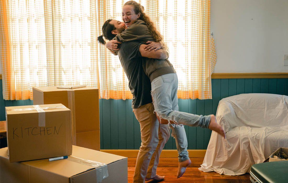 Man is Holding a Woman in His Arms in a Living Room — MoneySmith Group In Kingscliff, NSW