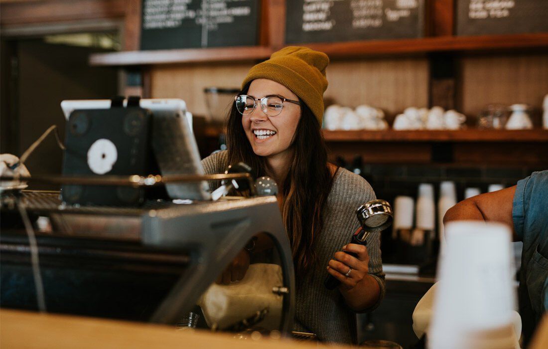 A Woman is Smiling While Making Coffee — MoneySmith Group In Kingscliff, NSW