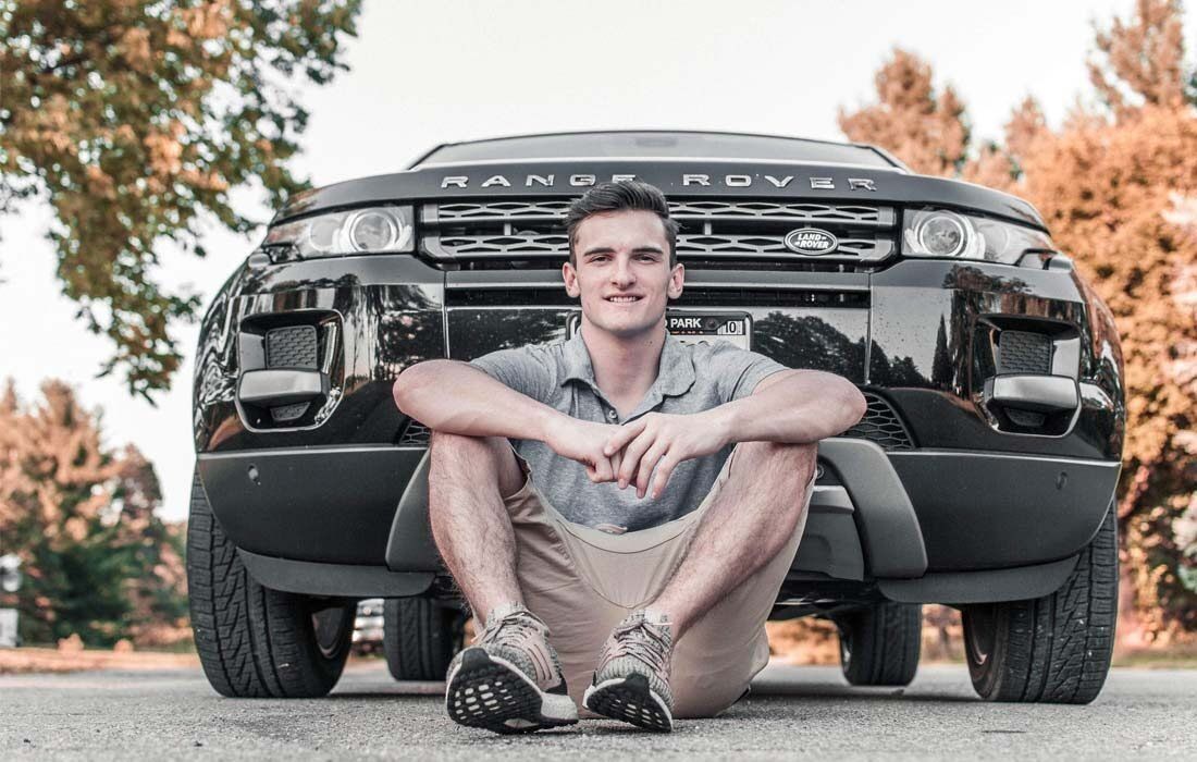 Young Man is Sitting on the Ground in Front of a Range Rover — MoneySmith Group In Kingscliff, NSW