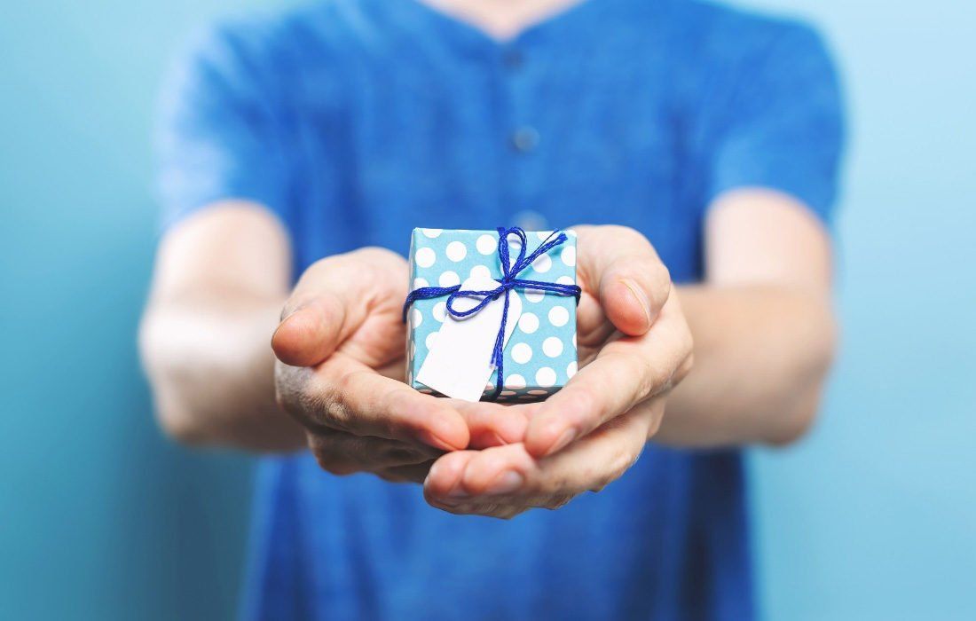A Man in a Blue Shirt is Holding a Small Box — MoneySmith Group In Kingscliff, NSW