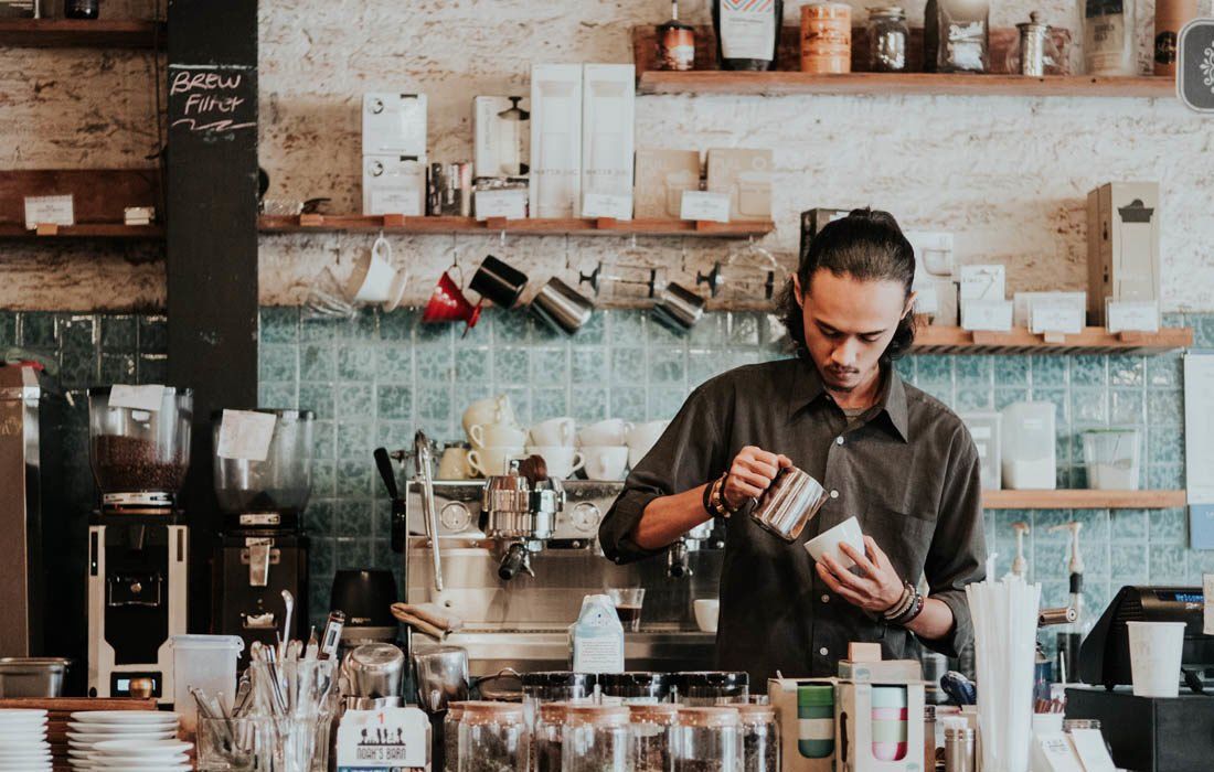 A Man is Pouring Milk Into a Cup in a Coffee Shop — MoneySmith Group In Kingscliff, NSW
