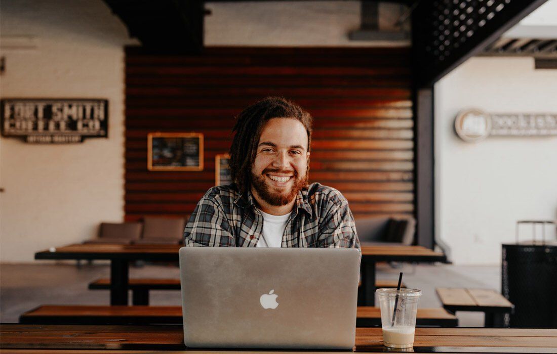 Man is Sitting at a Table Using a Laptop — MoneySmith Group In Kingscliff, NSW