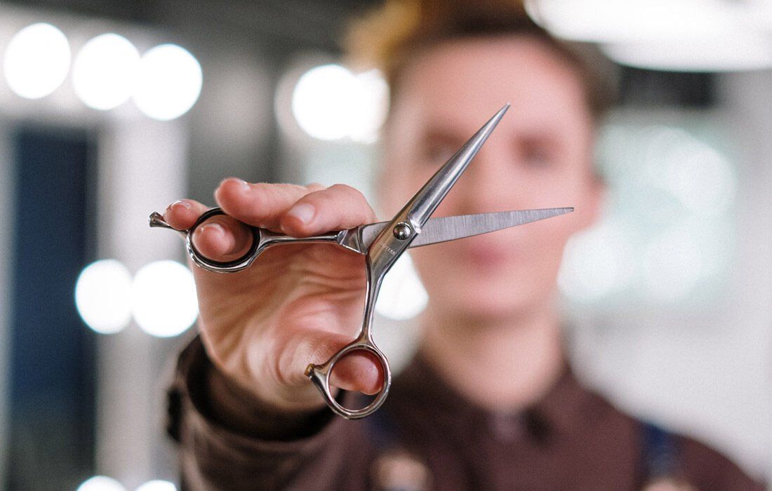 A Man is Holding a Pair of Scissors — MoneySmith Group In Kingscliff, NSW