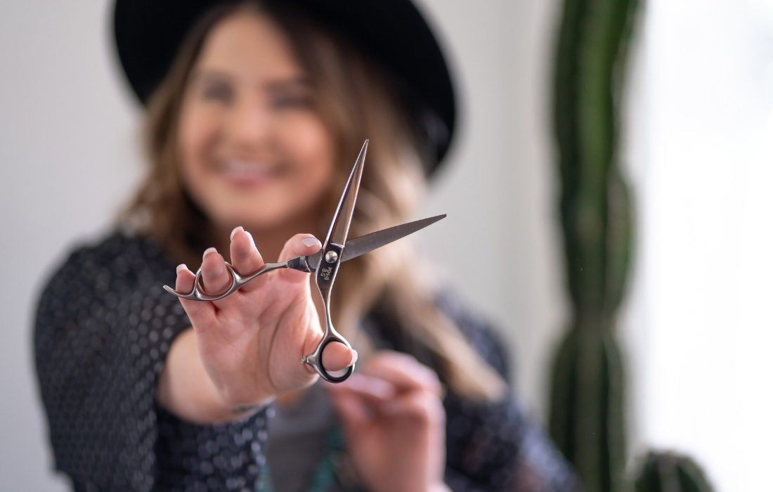 A Woman is Holding a Pair of Scissors — MoneySmith Group In Kingscliff, NSW