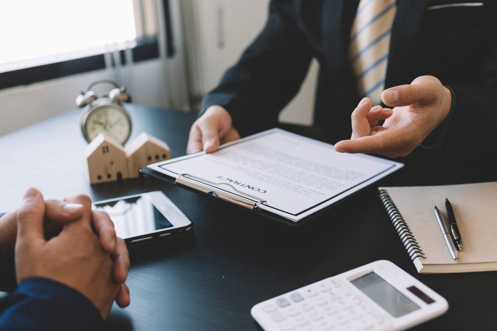 Two Men Are Sitting at a Table Looking at a Piece of Paper — MoneySmith Group In Kingscliff, NSW