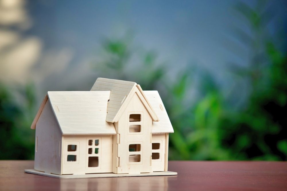 A Small Model House is Sitting on a Wooden Table — MoneySmith Group In Tweed Heads, NSW