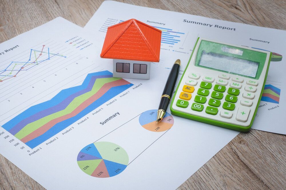 A Model House is Sitting on Top of a Table Next to a Calculator and a Pen — MoneySmith Group In Banora Point, NSW