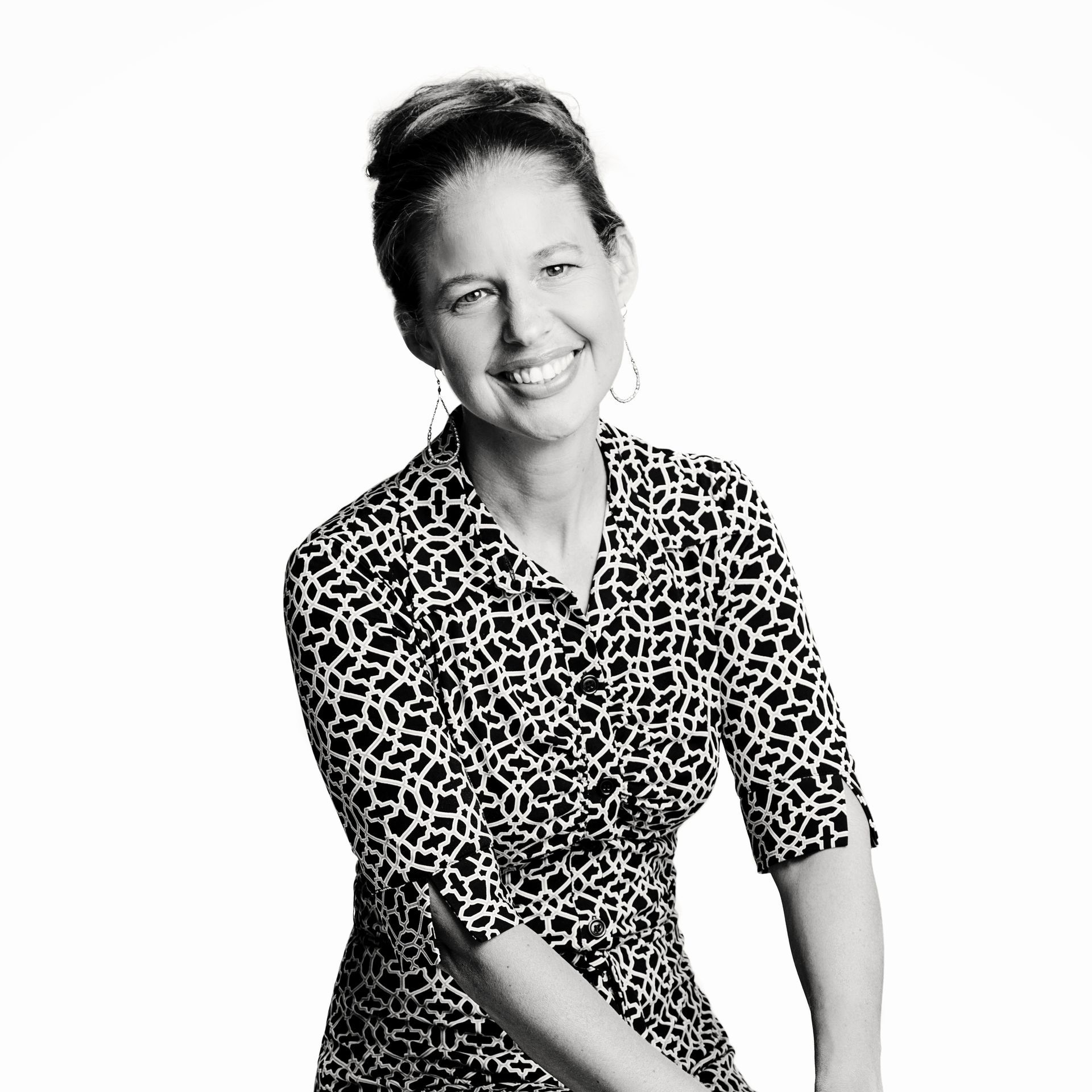 A woman is sitting at a desk with a laptop and a vase of flowers.