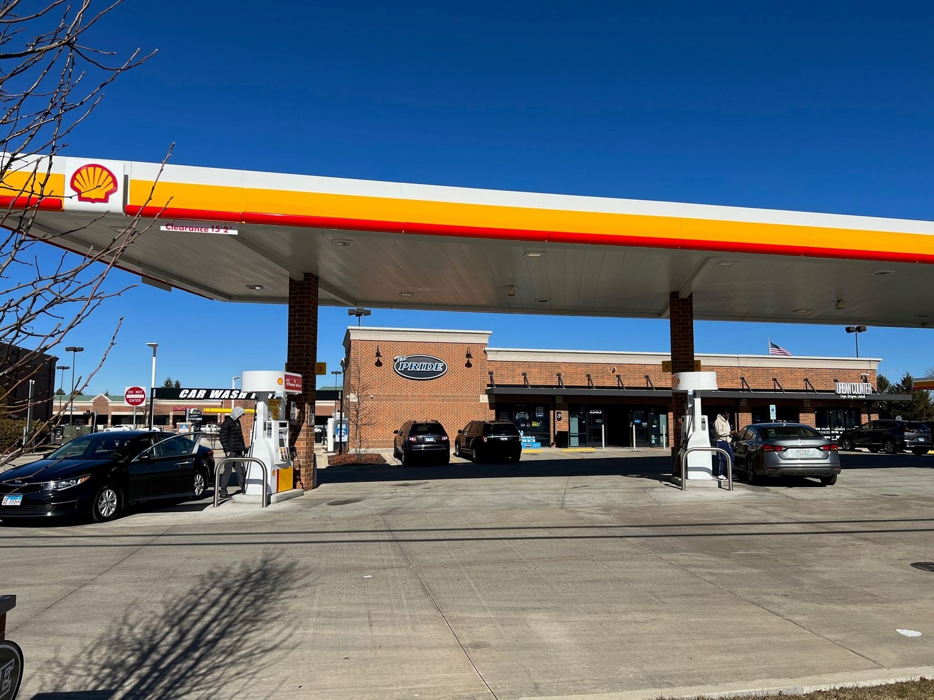 A brick building with tables and umbrellas in front of it.
