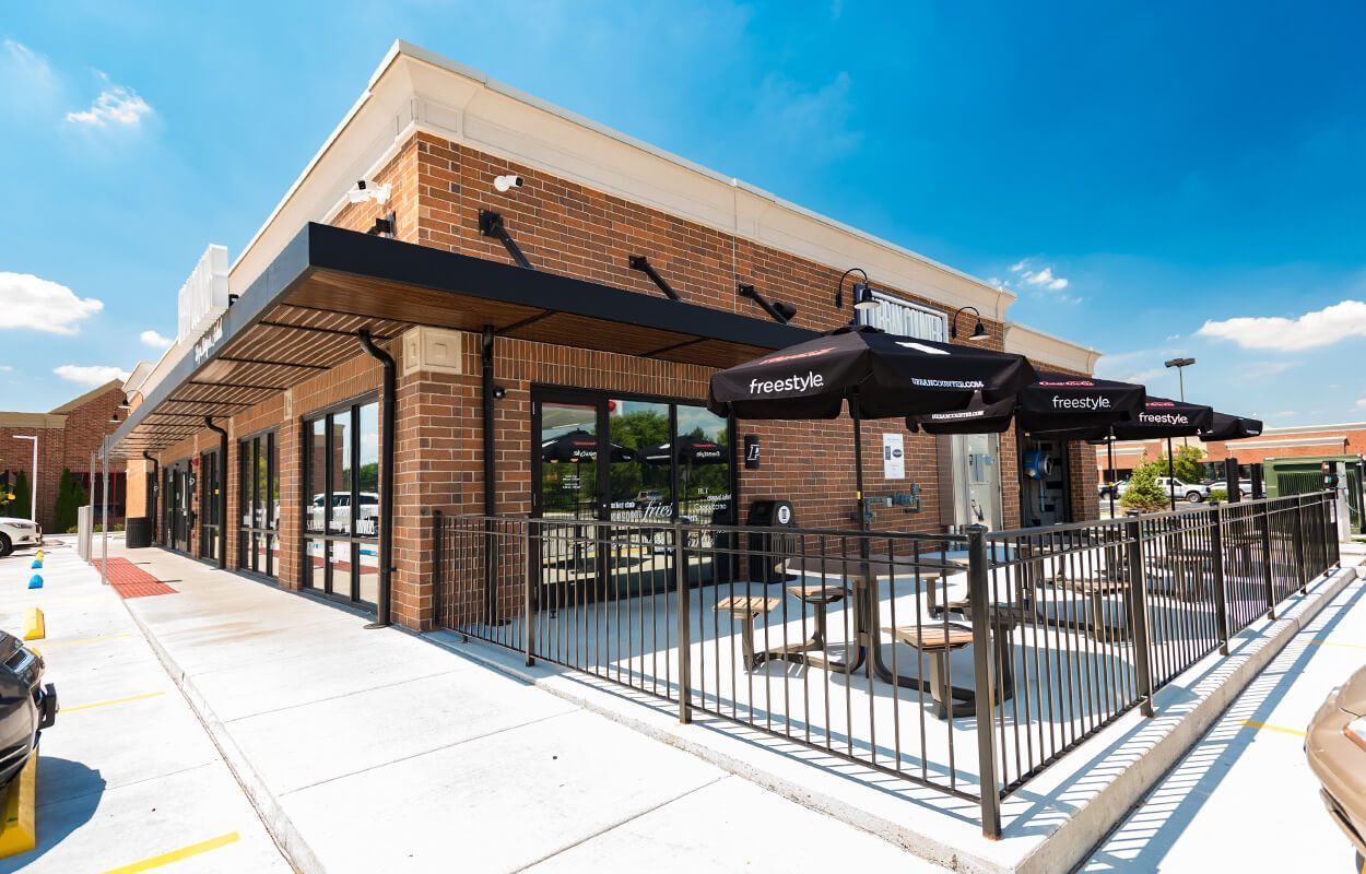 A brick building with tables and umbrellas in front of it.