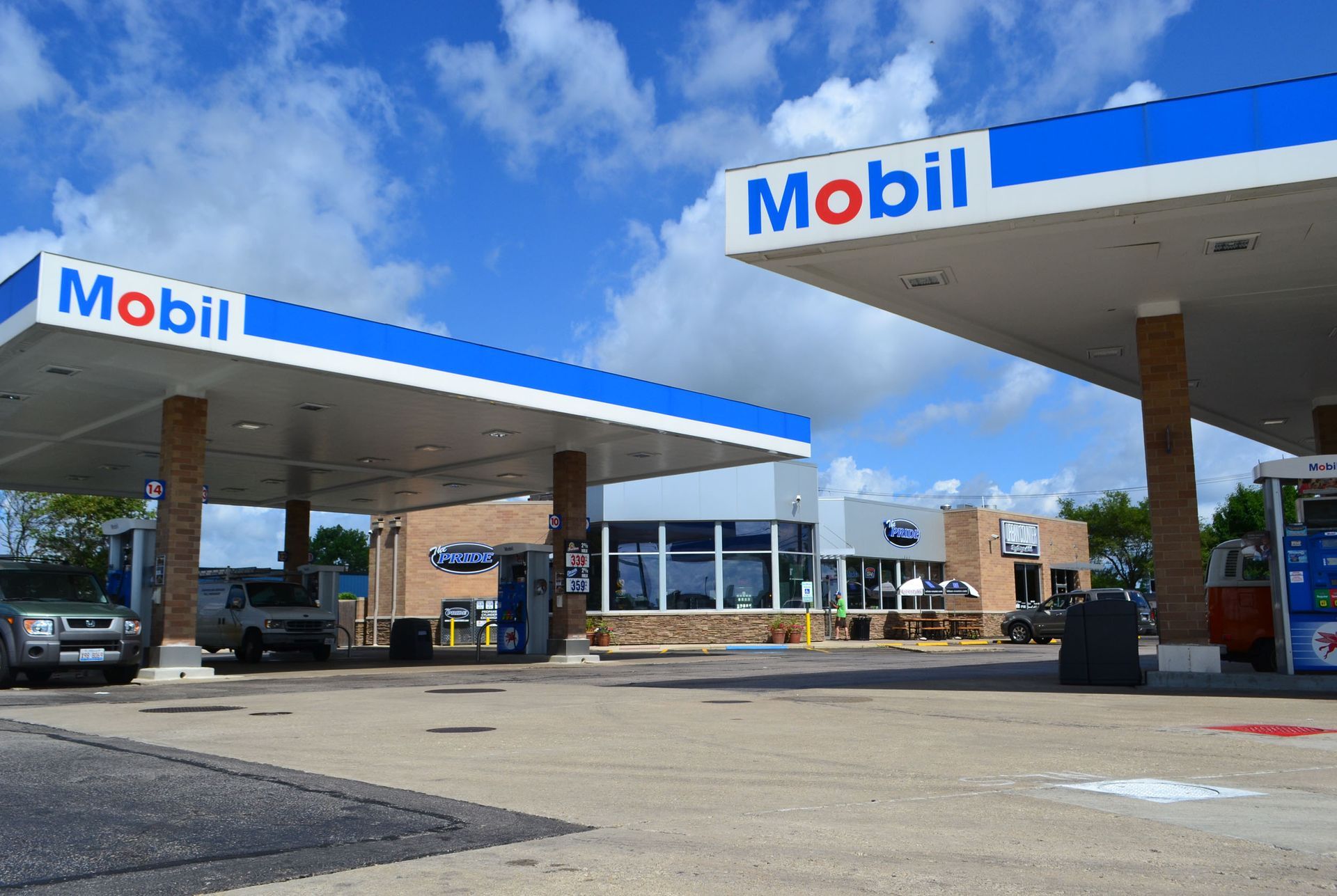 Two cars are parked in front of a mobil gas station
